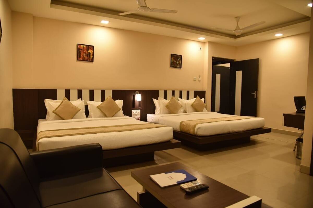 A hotel room with two beds, a desk, a chair, and a ceiling fan.