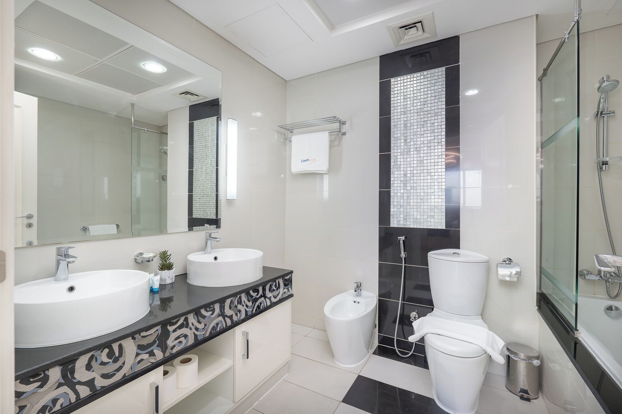 A modern bathroom with two sinks, a toilet, and a shower.
