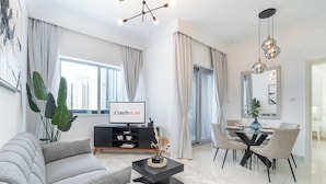Een moderne woonkamer met een bank, salontafel, televisie en een eethoek met stoelen en een glazen tafel.