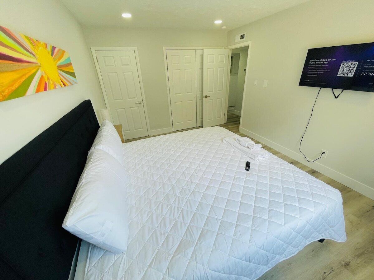 A hotel room with a bed, a TV mounted on the wall, and a door leading to another room.