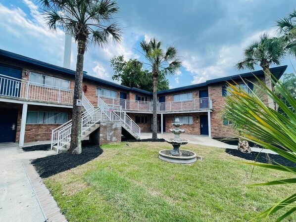 A building with a central courtyard, a fountain, and palm trees. - Perfect Vacation walk to the beach 1 (Myrtle Beach)