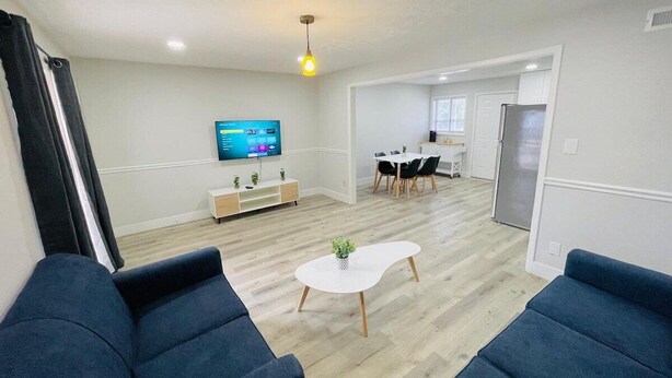 A modern living room with a flat-screen TV, a coffee table, and blue sofas. - Perfect Vacation walk to the beach 5 (Myrtle Beach)