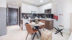 A modern kitchen with a central island, built-in appliances, and a dining area with a glass table and chairs. - NEW Lisiting | Miracle Garden | Great Location (Dubai)