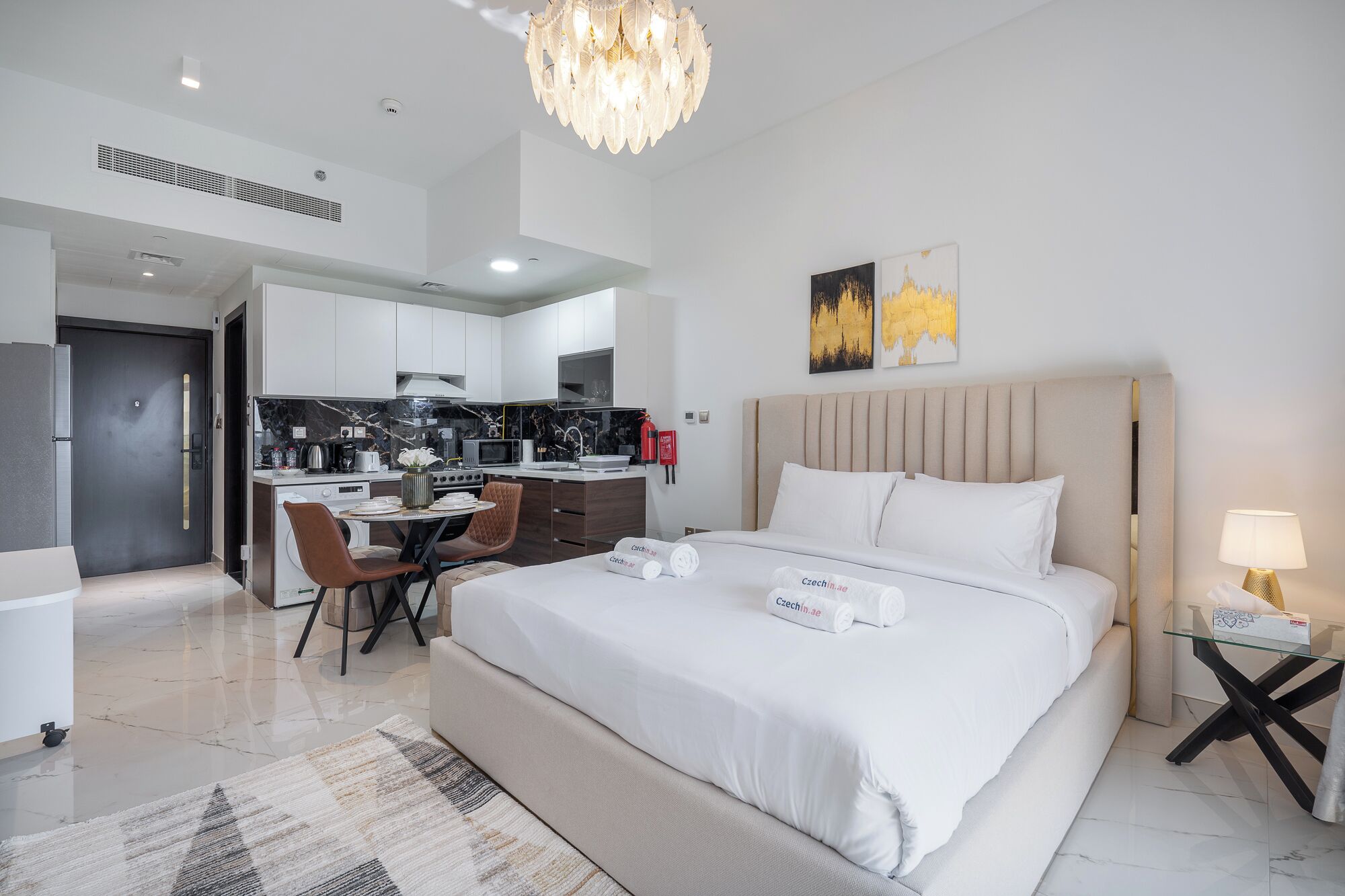 Ein modernes Hotelzimmer mit einem großen Bett, einer Essecke und einer Küche.
