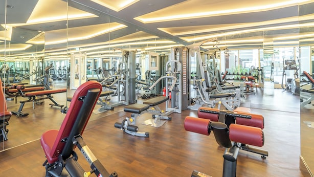 A modern gym with various exercise machines, large mirrors, and a wooden floor. - NEW Lisiting | Miracle Garden | Great Location (Dubai)