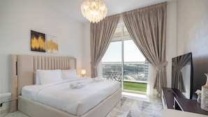 A modern hotel room with a large bed, a TV, a balcony with a city view, and a chandelier. - NEW Lisiting | Miracle Garden | Great Location (Dubai)