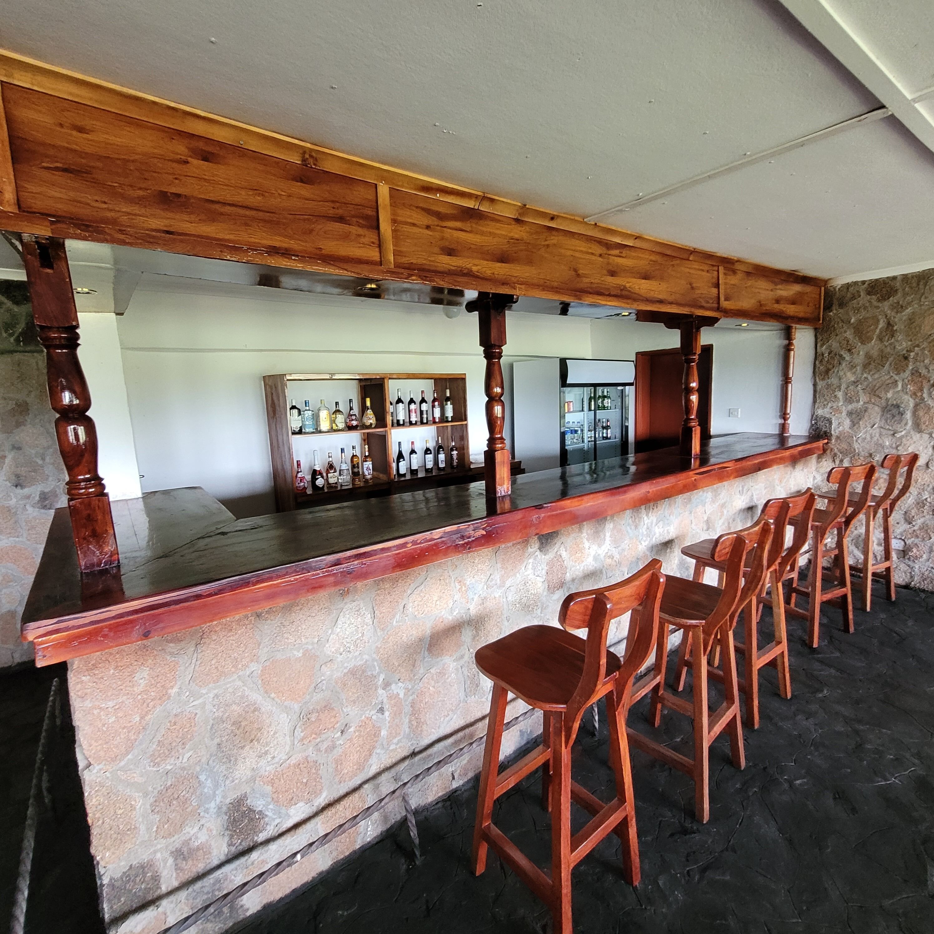 Un área de bar con sillas de madera y pared de piedra.
