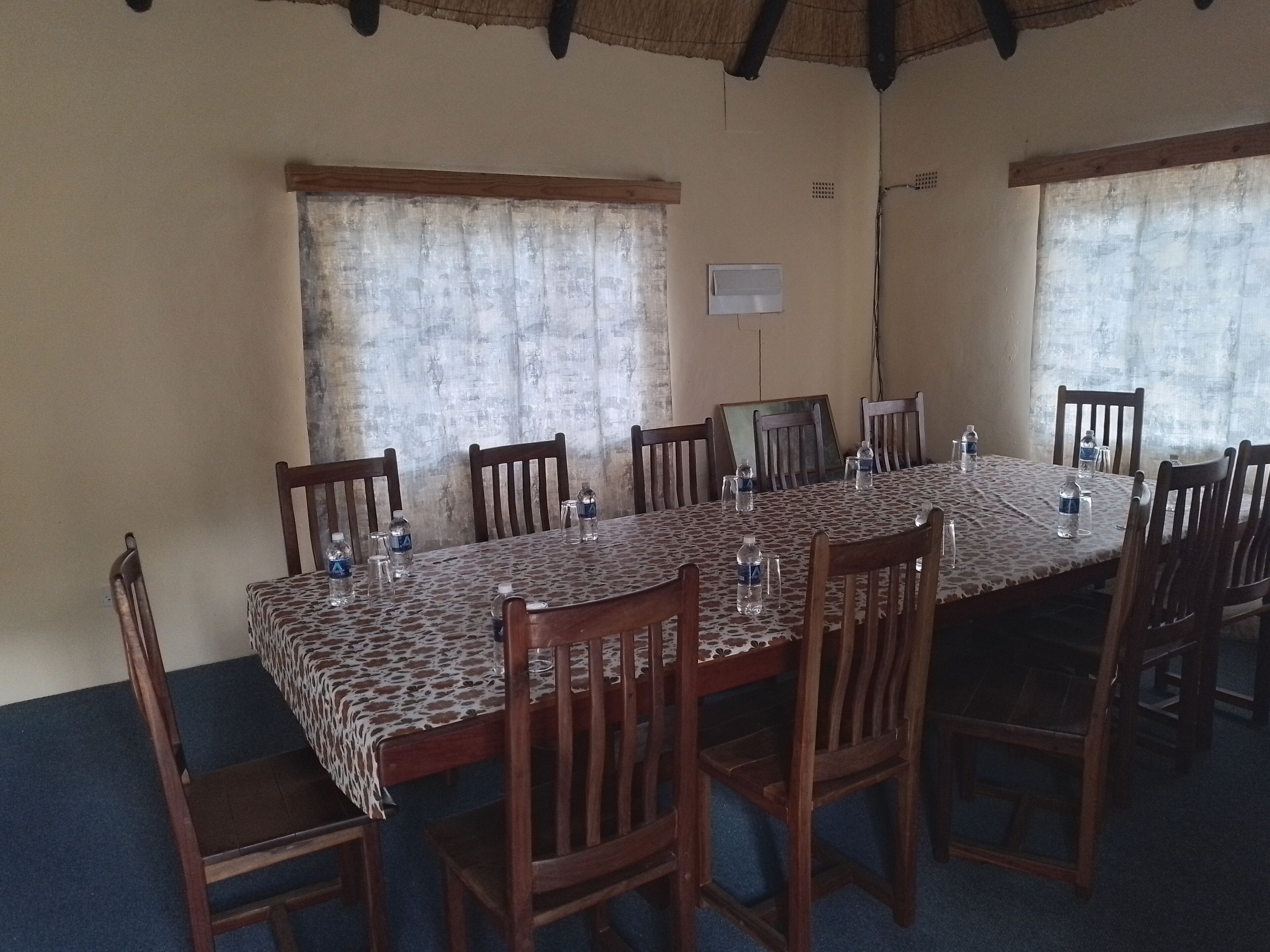 A conference room with a long table, wooden chairs, and water bottles.