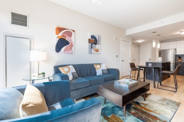 Una sala de estar moderna con un sofá azul, una mesa de centro y arte abstracto en la pared.