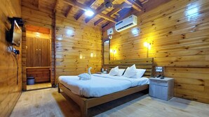 Un dormitorio de cabaña de madera con cama, mesita de noche y un mueble pequeño.