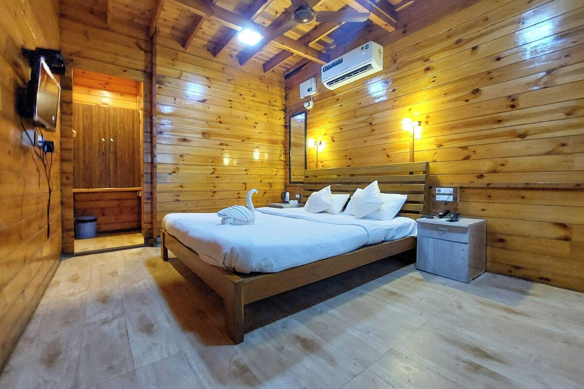 Une chambre dans une cabane en bois, avec un lit, une table de chevet et un petit meuble.