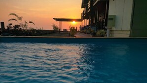 Una piscina al atardecer con un edificio al fondo.