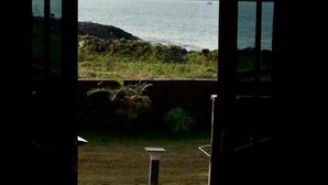 Una abertura que da a una vista de un lago con orilla rocosa y una cadena montañosa distante.