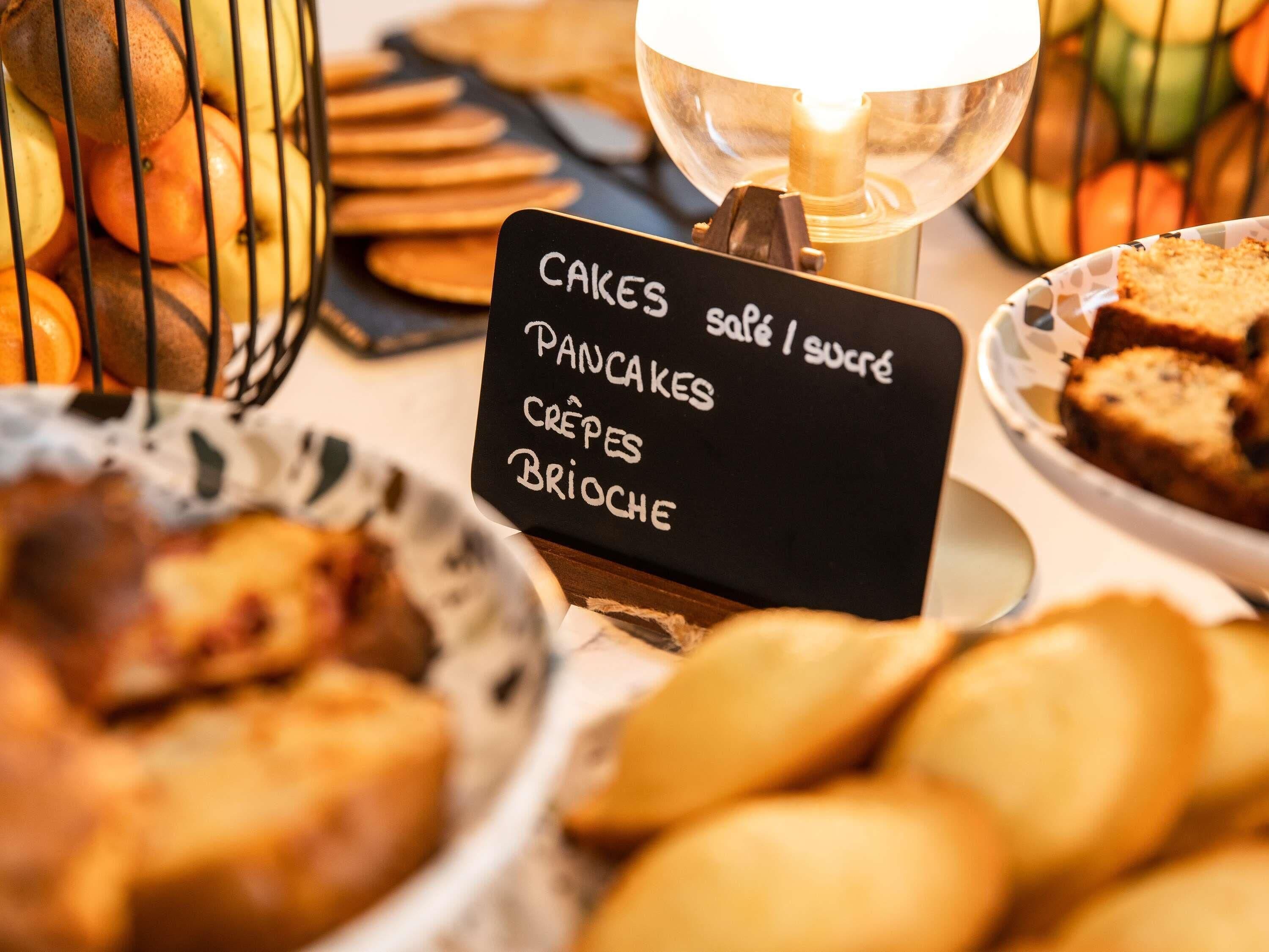 A sign listing breakfast items including cakes, pancakes, crepes, and brioche.