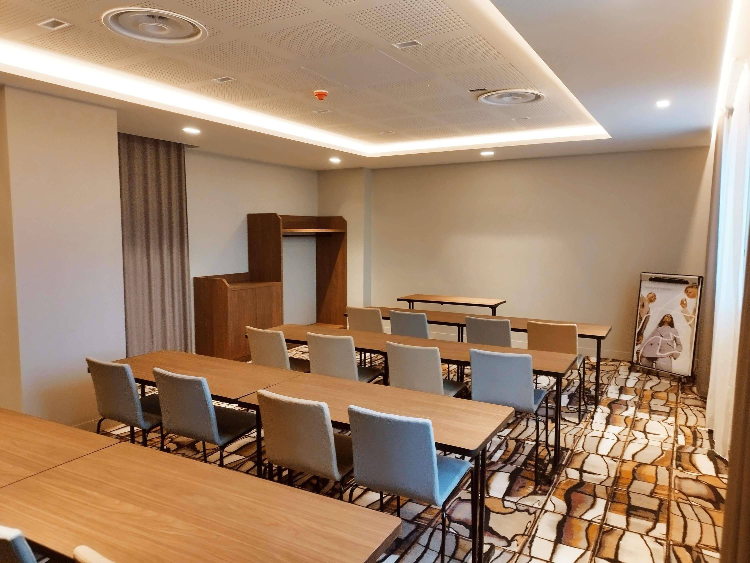 Ein Konferenzraum mit mehreren Tischen, Stühlen, einem Rednerpult und einem gemusterten Boden.