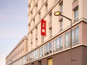Un hôtel à plusieurs étages, reconnaissable à son grand panneau rouge indiquant qu’il s’agit d’un hôtel Ibis.