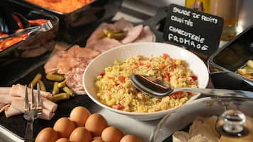 Un buffet proposant divers plats, notamment une salade de couscous, des œufs et des tranches de viande.