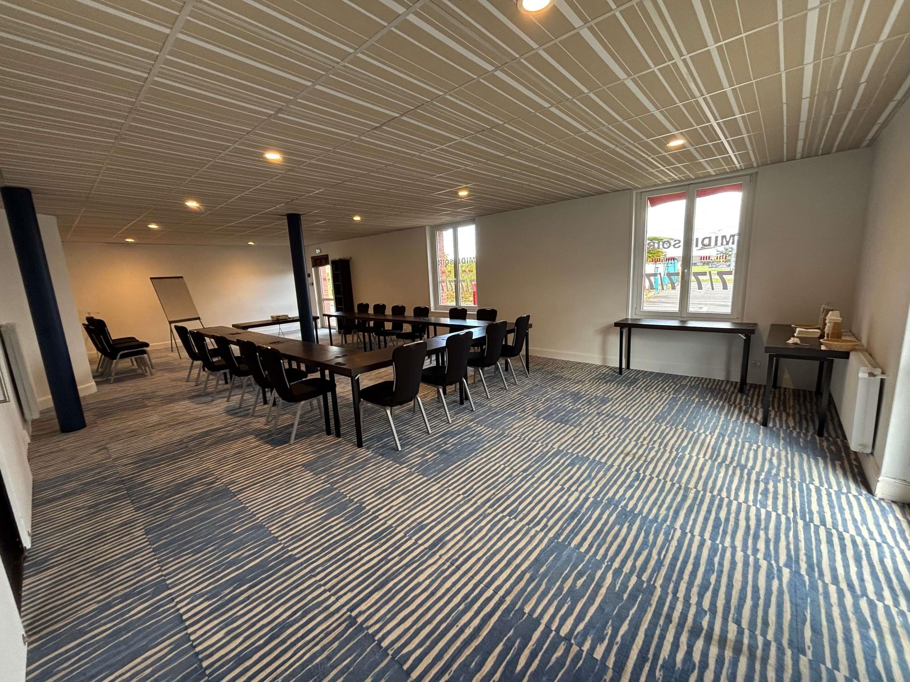 Un salón de conferencias con una larga mesa, sillas, una pizarra y una ventana con vistas.
