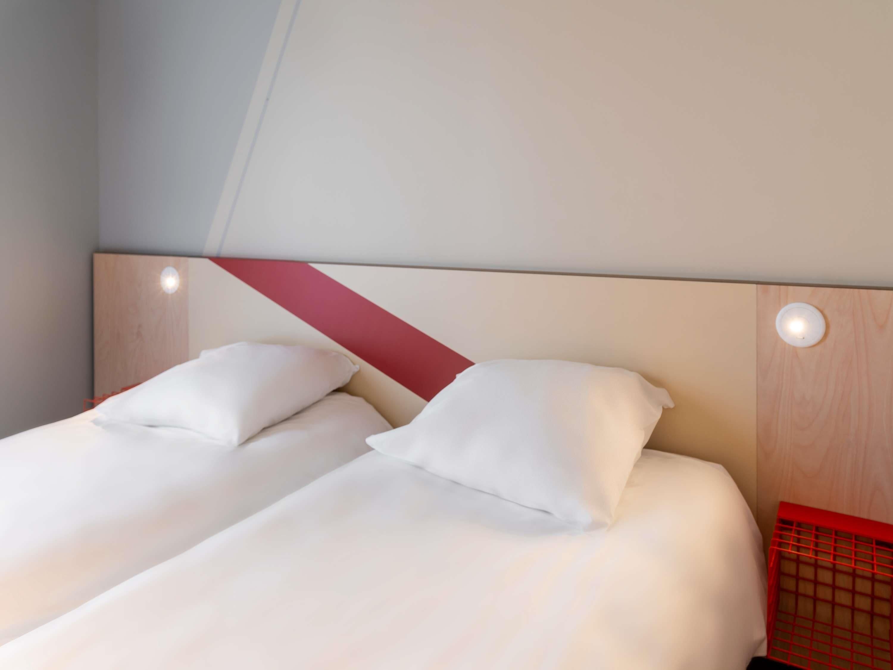 A hotel room with two beds, each with white bedding and pillows.
