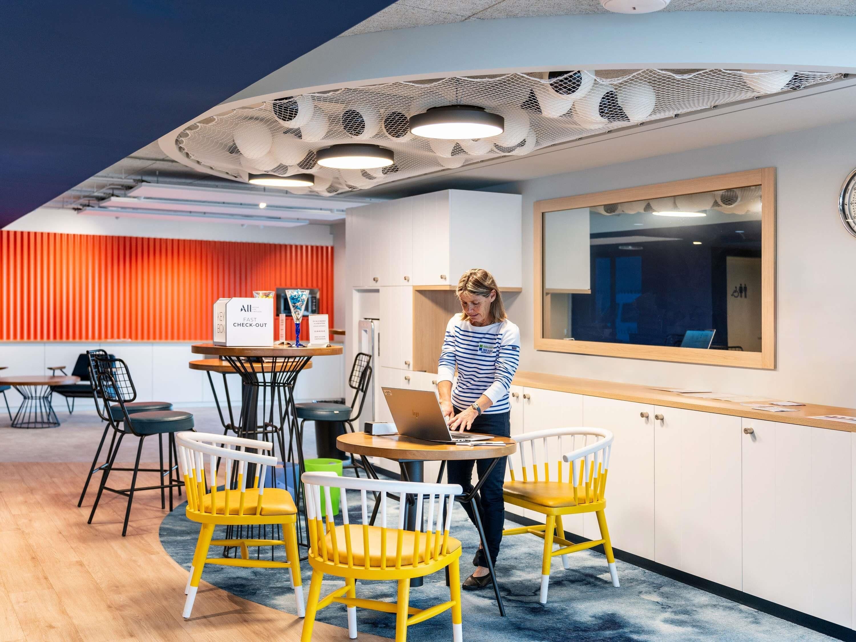 Un espace de bureau moderne avec une table ronde, des chaises, un ordinateur portable et un panneau indiquant une zone de paiement rapide.