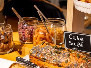 A cake display with a sign reading 'Cake sablé' and various jars of food items. - Ibis Budget Morlaix (Morlaix)