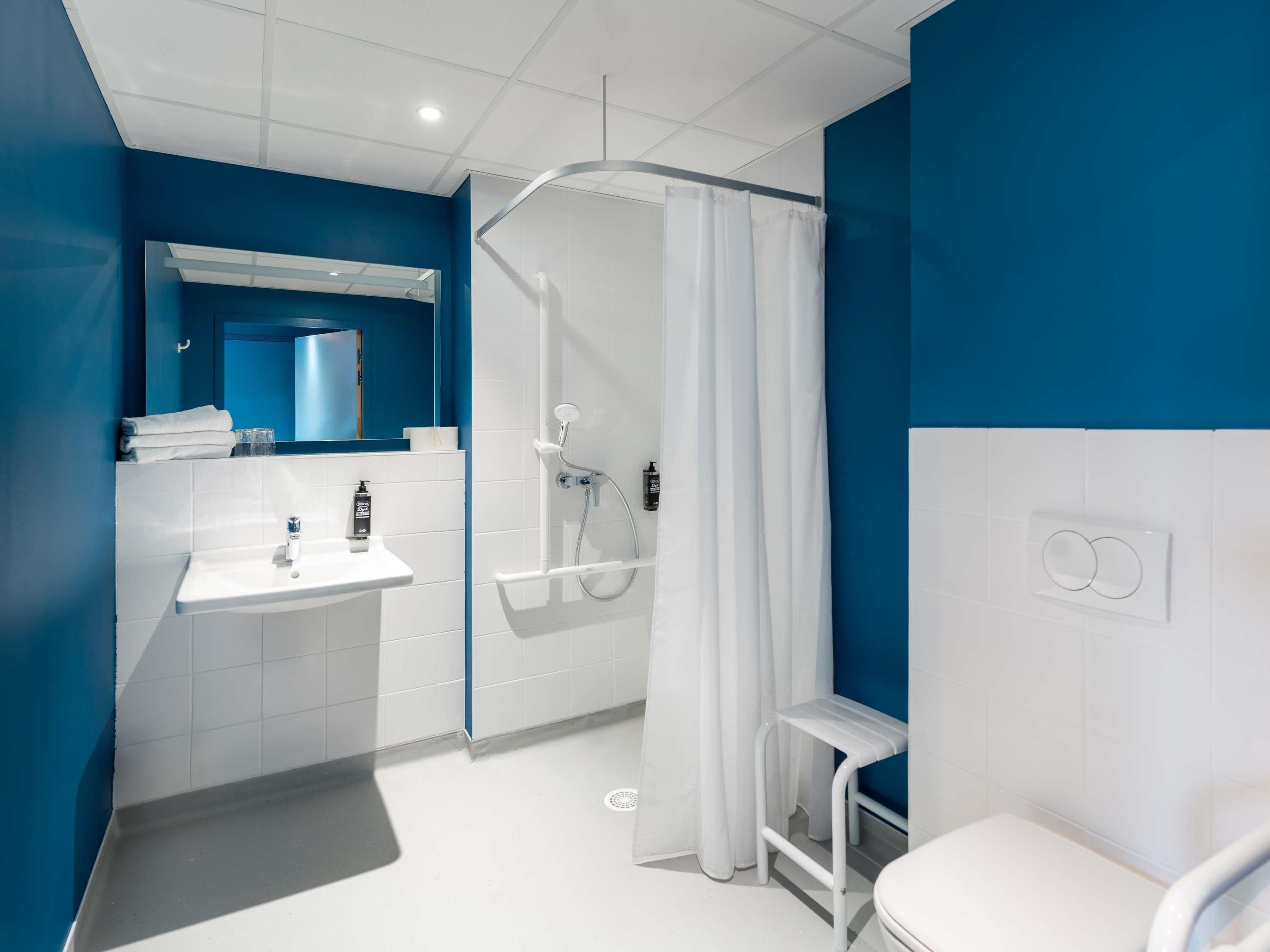 Une salle de bain moderne avec un lavabo blanc, un miroir et des toilettes.