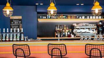 A bar area with three black chairs, a counter with various bottles, and a coffee machine.