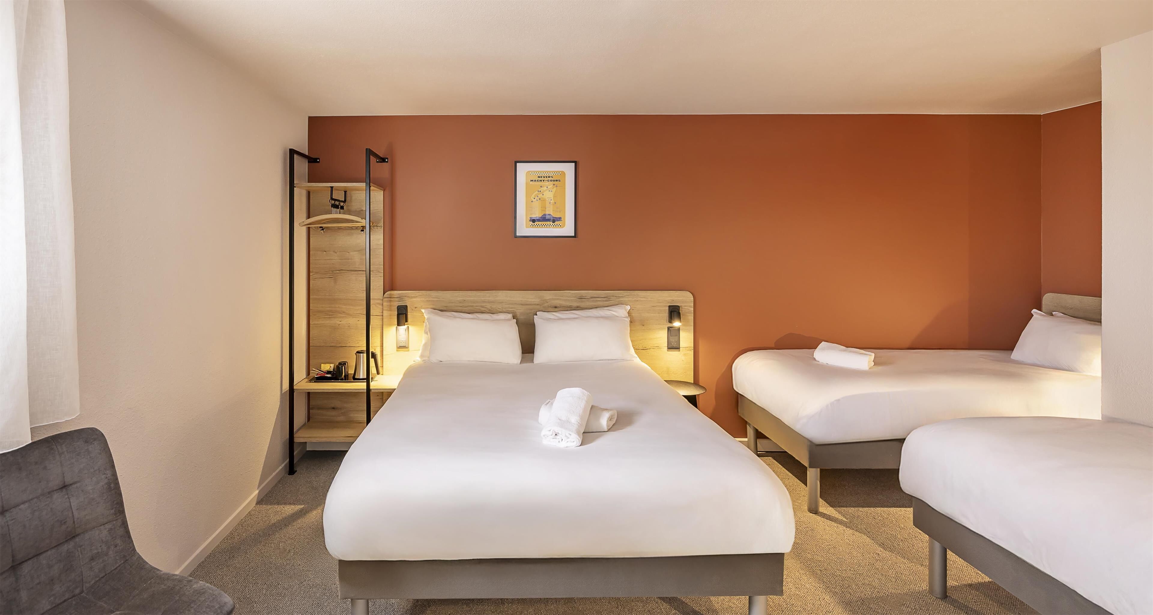 Une chambre d’hôtel avec un grand lit, deux petits lits, un coin salon et une salle de bain.
