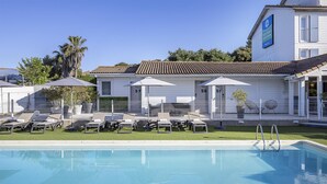 Un hôtel doté d’une piscine, de chaises longues et de parasols.