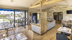 Un espace de restauration moderne avec des poutres en bois, un comptoir de bar et une vue sur un quartier résidentiel.