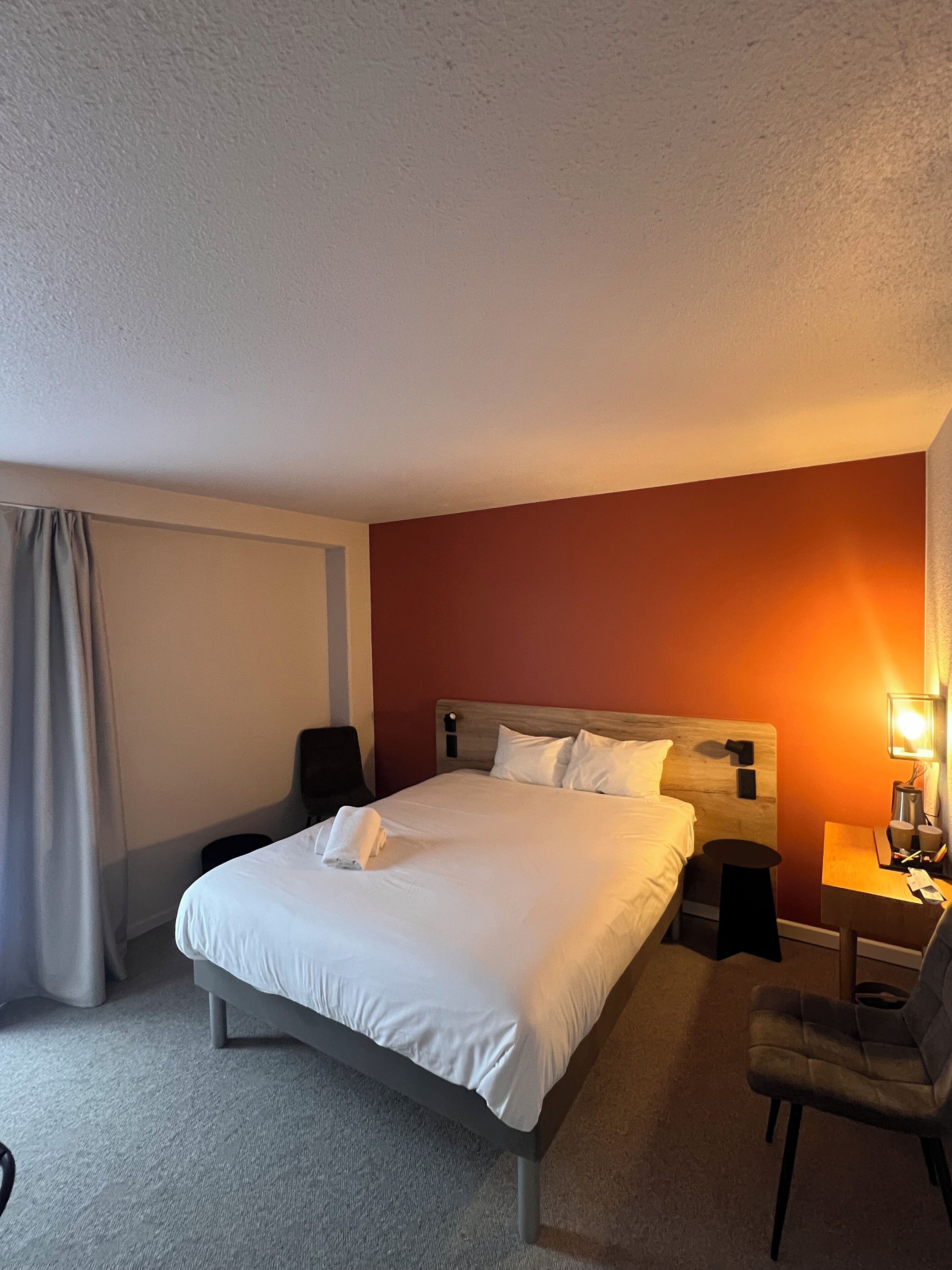 Une chambre d’hôtel avec un grand lit, une table de chevet avec une lampe, une chaise et une petite table.