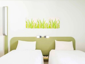 Two single beds with white bedding, a wall-mounted artwork, and a minimalist aesthetic.