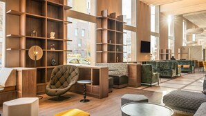 A modern interior with wooden shelving, seating, and a large window. - Mercure Achères St Germain En Laye (Acheres)