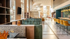 A modern interior with a bar area, seating, and large windows. - Mercure Achères St Germain En Laye (Acheres)