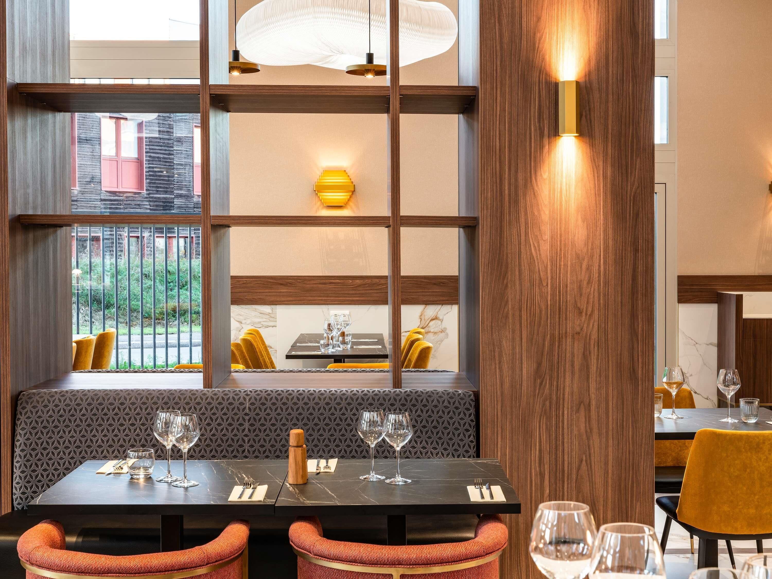 A restaurant with a modern interior, featuring a black marble table, yellow cushioned chairs, and a patterned wall.