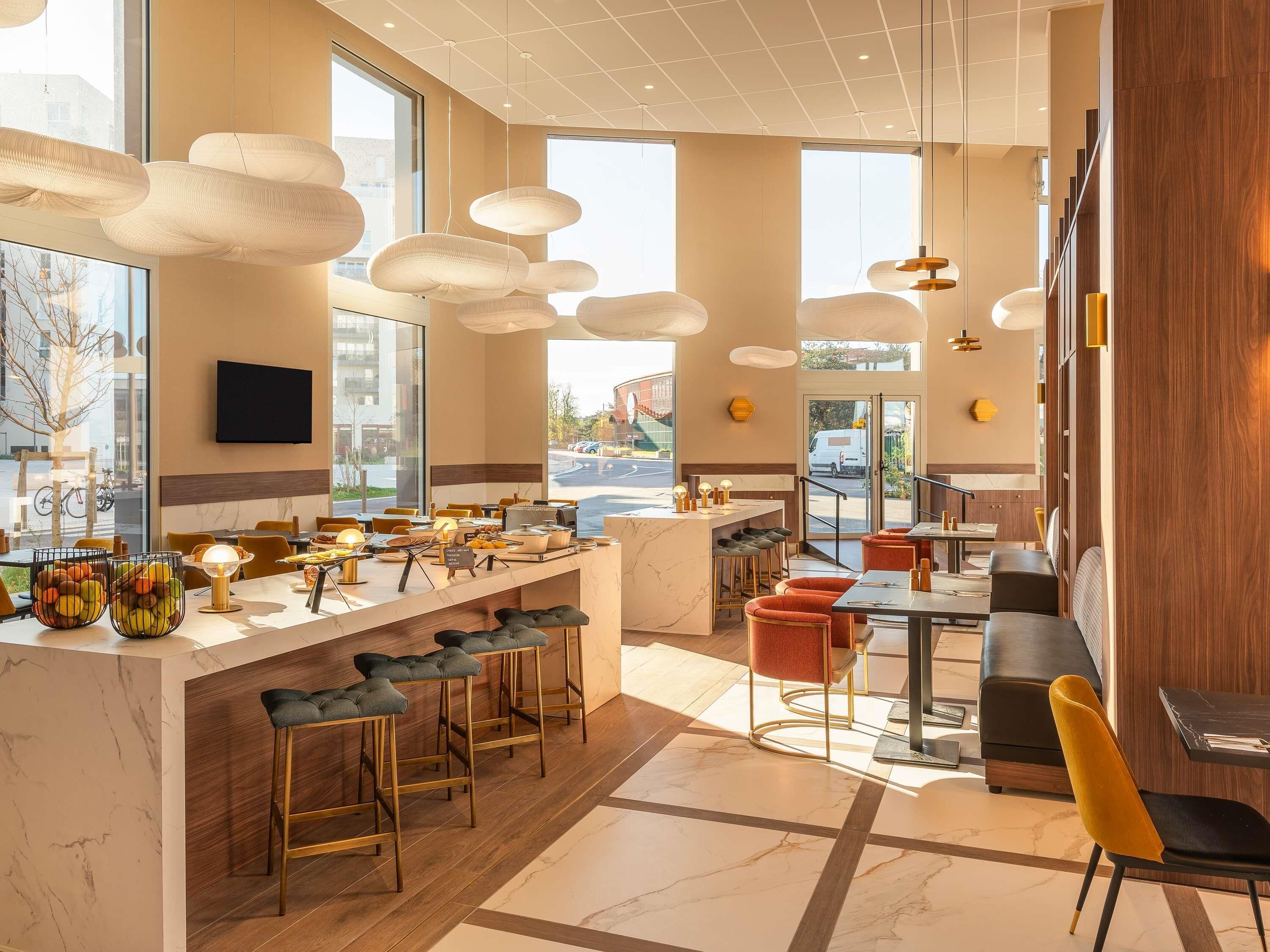 A modern bar area with a marble countertop, multiple stools, and pendant lighting.