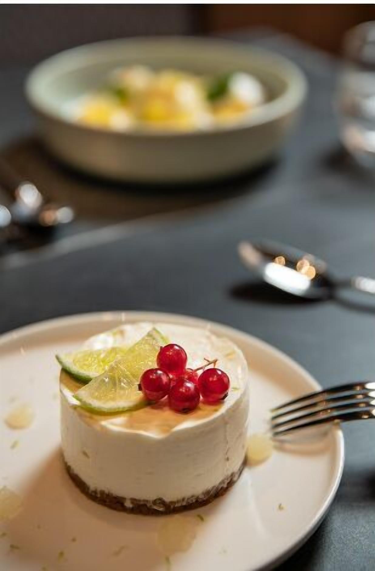 A dessert on a plate with lime slices and red berries on top.