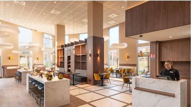 A modern hotel lobby with marble reception desks, a bar area, and seating arrangements. - Mercure Achères St Germain En Laye (Acheres)
