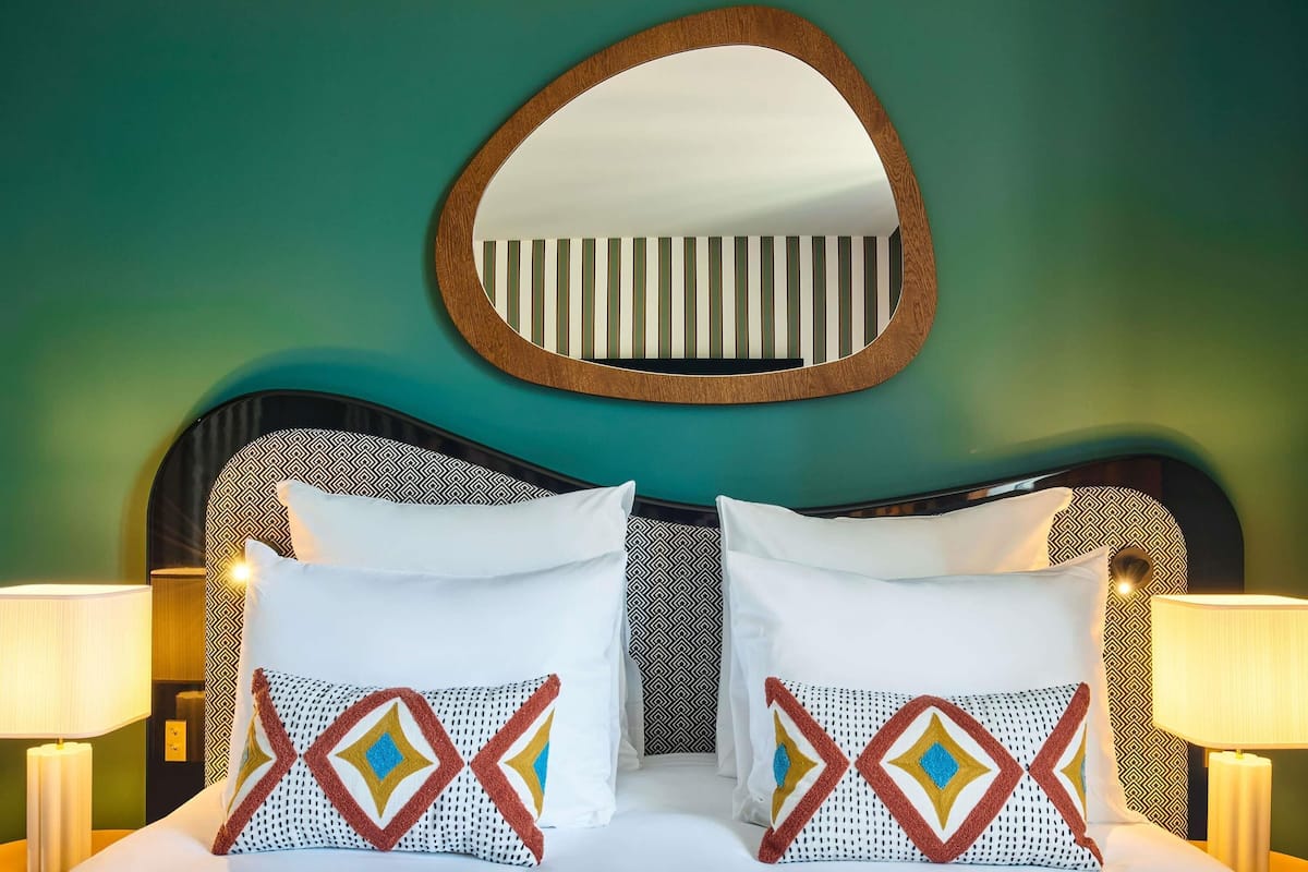 A bed with two pillows, a mirror, and two bedside lamps.