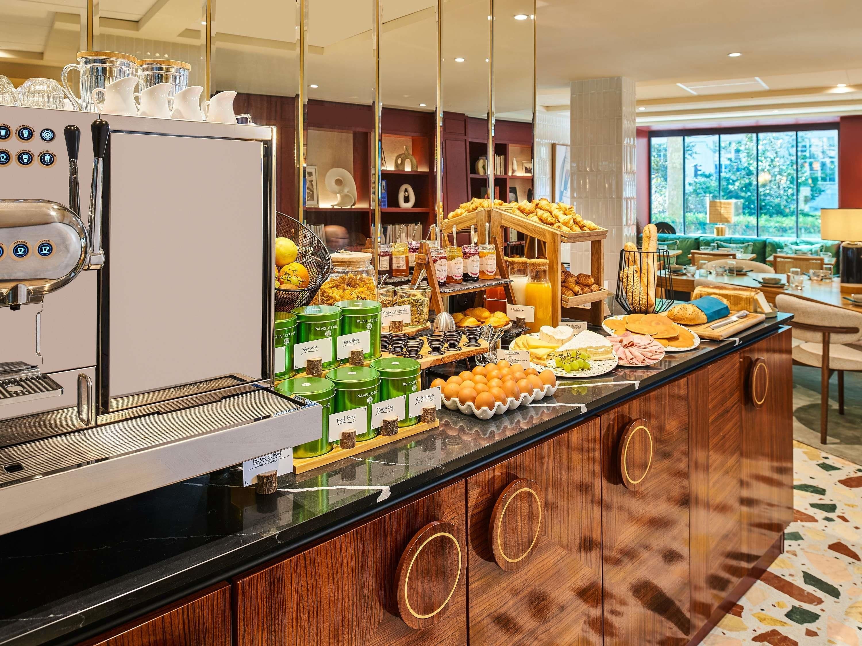 Een ontbijtbuffet met een koffieapparaat, diverse gerechten en uitzicht op het landschap.