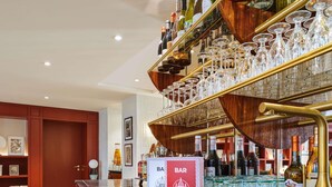 A bar area with a polished bar counter, wine bottles, and glasses. - Mercure Paris Butte Montmartre Basilique (Paris)