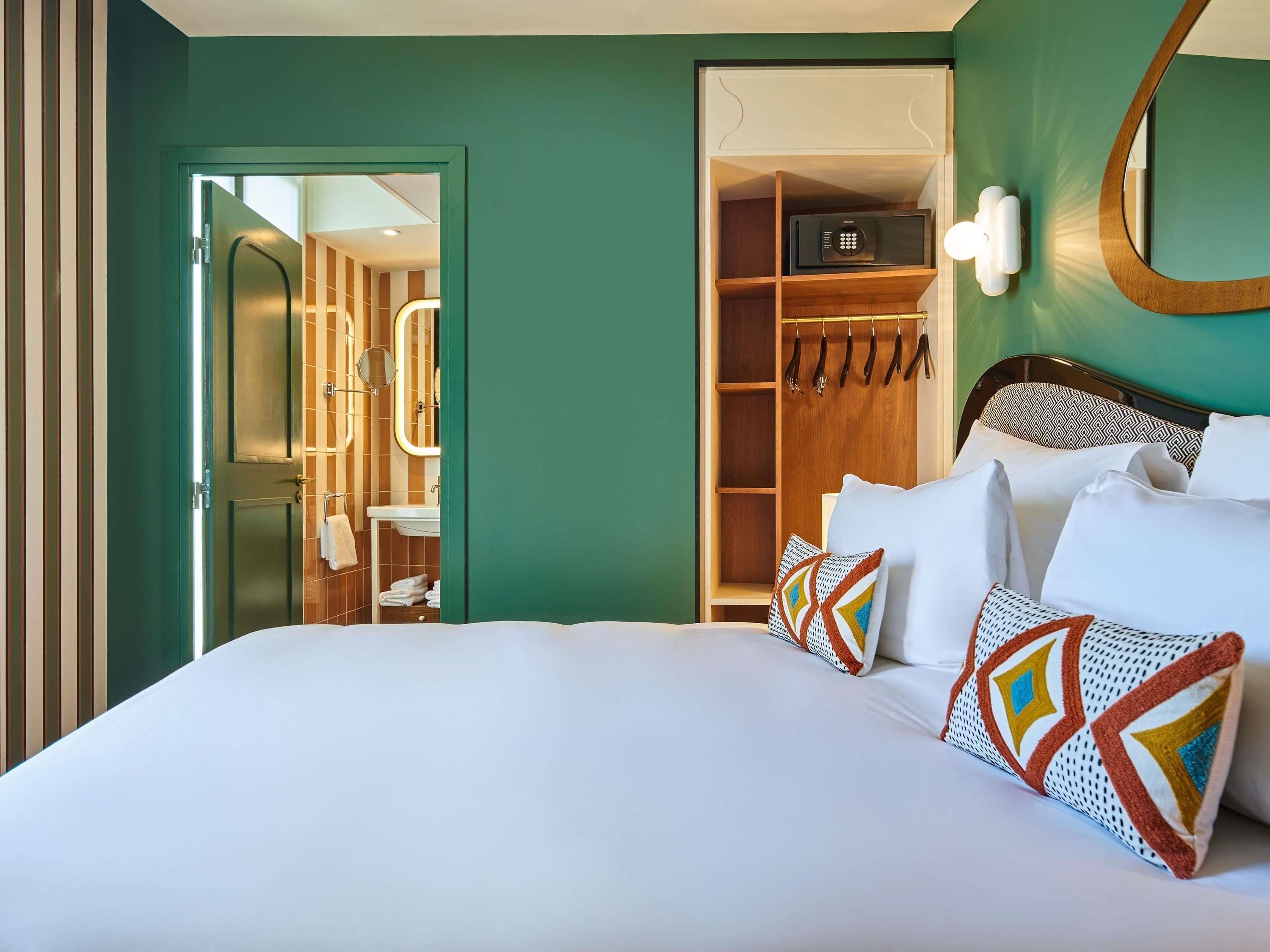 A hotel room with a large bed, a walk-in closet, a microwave, and a bathroom visible through an open door.