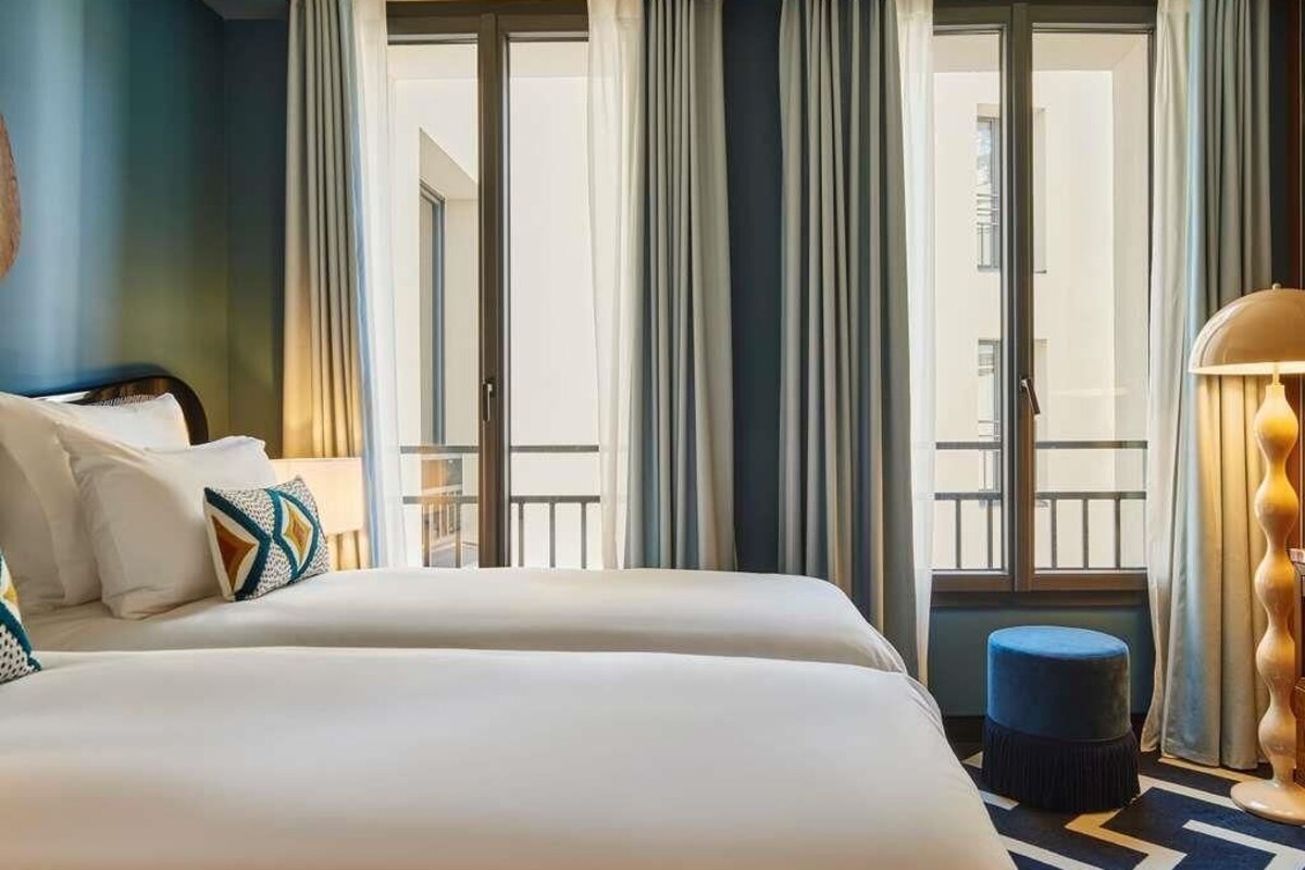Ein Hotelzimmer mit zwei Betten, einem Balkon und Blick auf die Stadt.