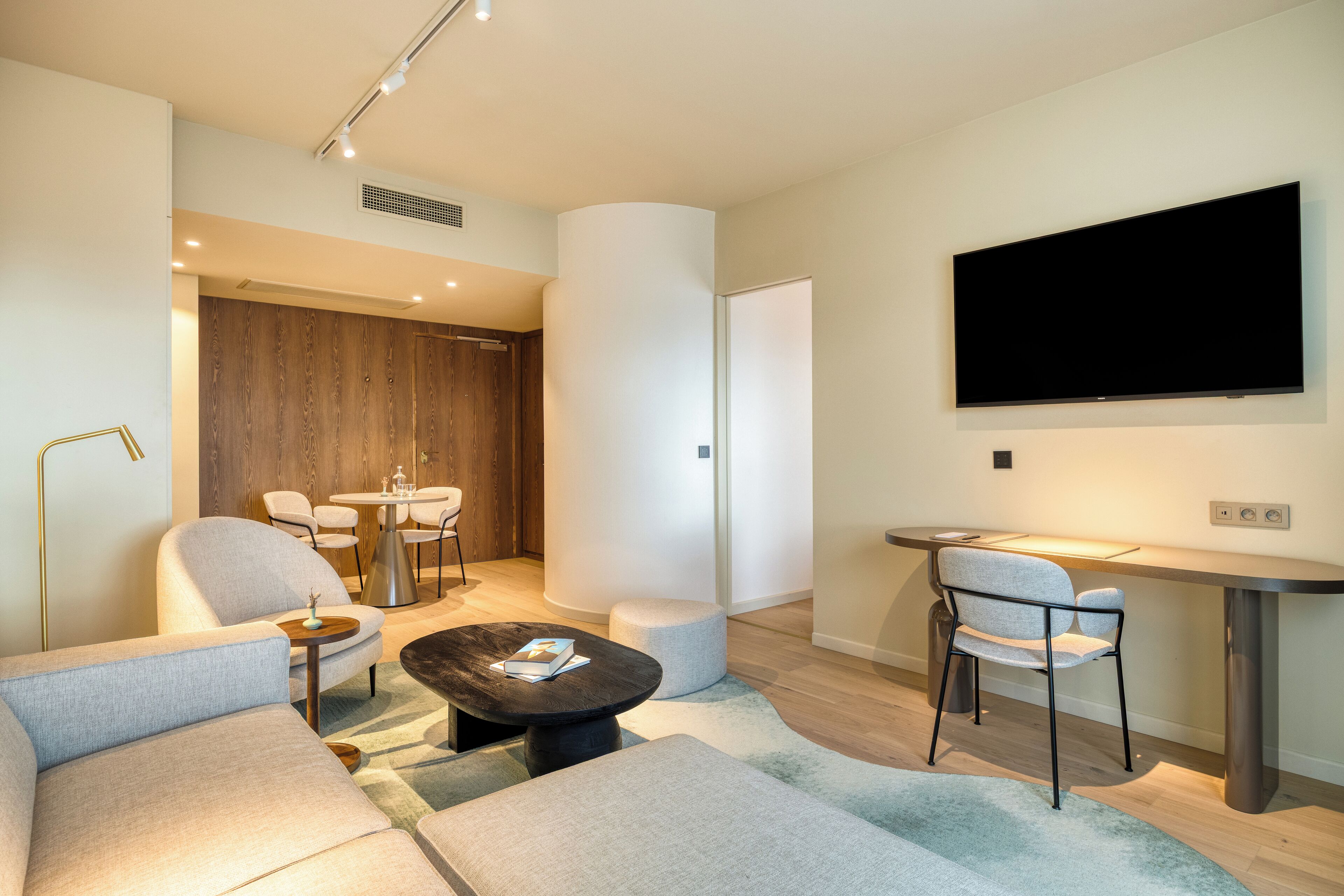 A modern living room with a sofa, coffee table, and a dining area with chairs and a table.