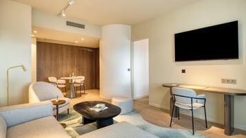 A modern living room with a sofa, coffee table, and a dining area with chairs and a table.