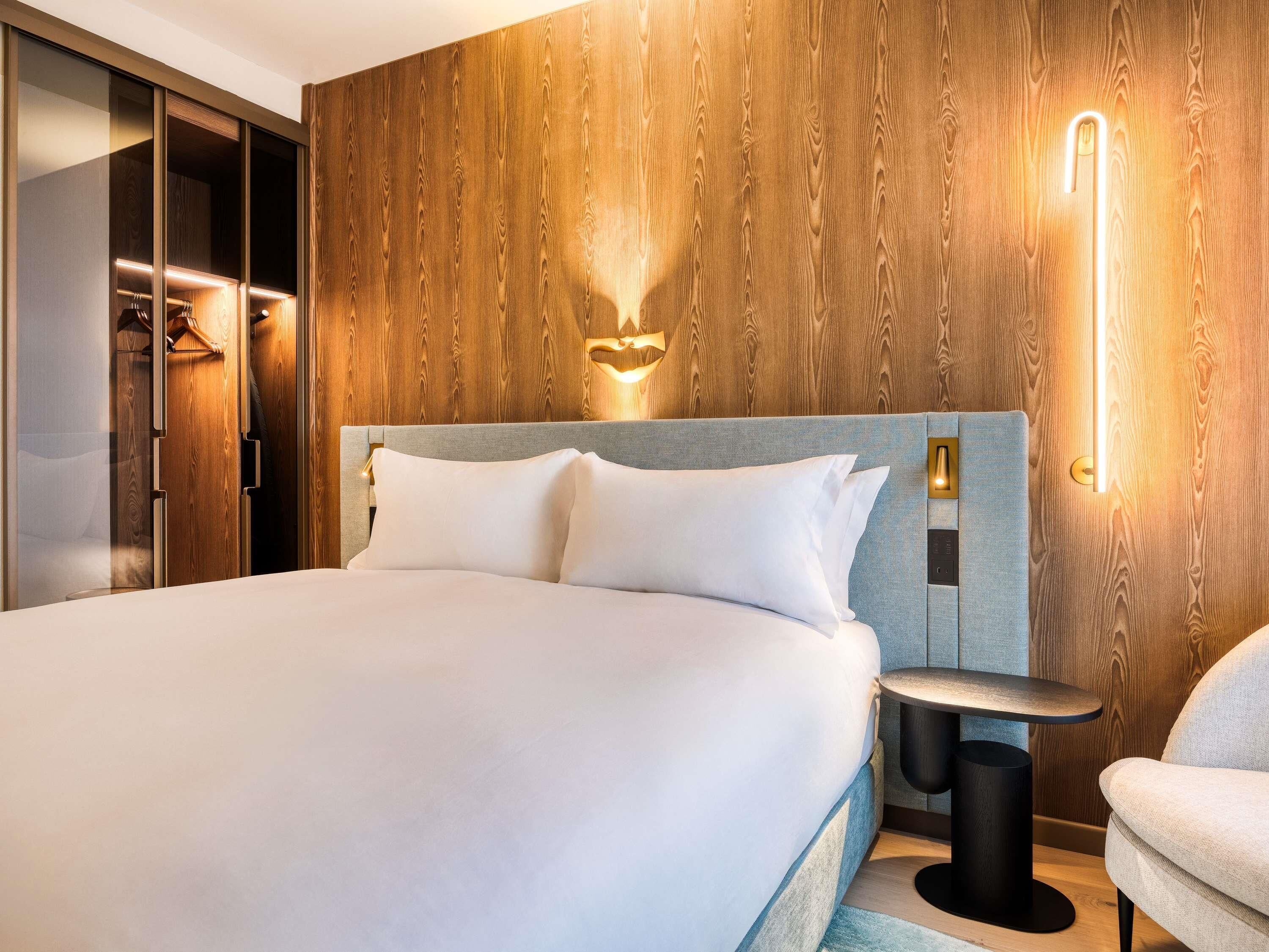 Een moderne hotelkamer met een groot bed, een wand van houten panelen en een klein bijzettafeltje.