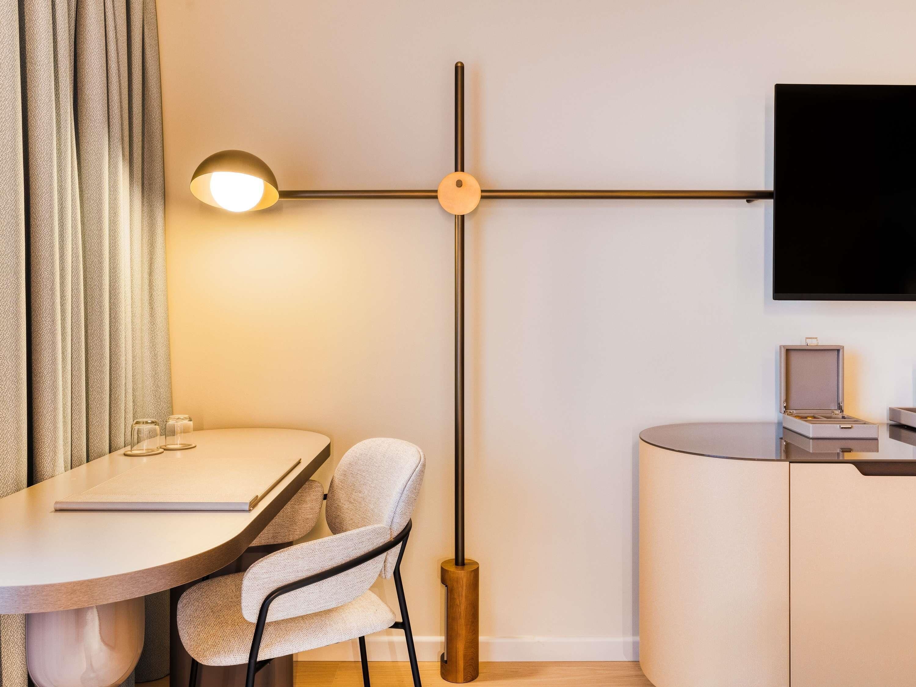 A modern room with a round dining table, a chair, a floor lamp, a TV, and a small cabinet.