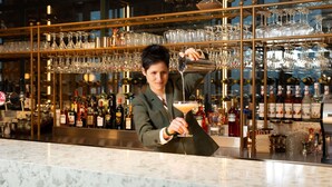 A bartender pouring a drink at a bar with a well-stocked wine and liquor shelf in the background. - Mövenpick hotel Brussels Airport (Zaventem)