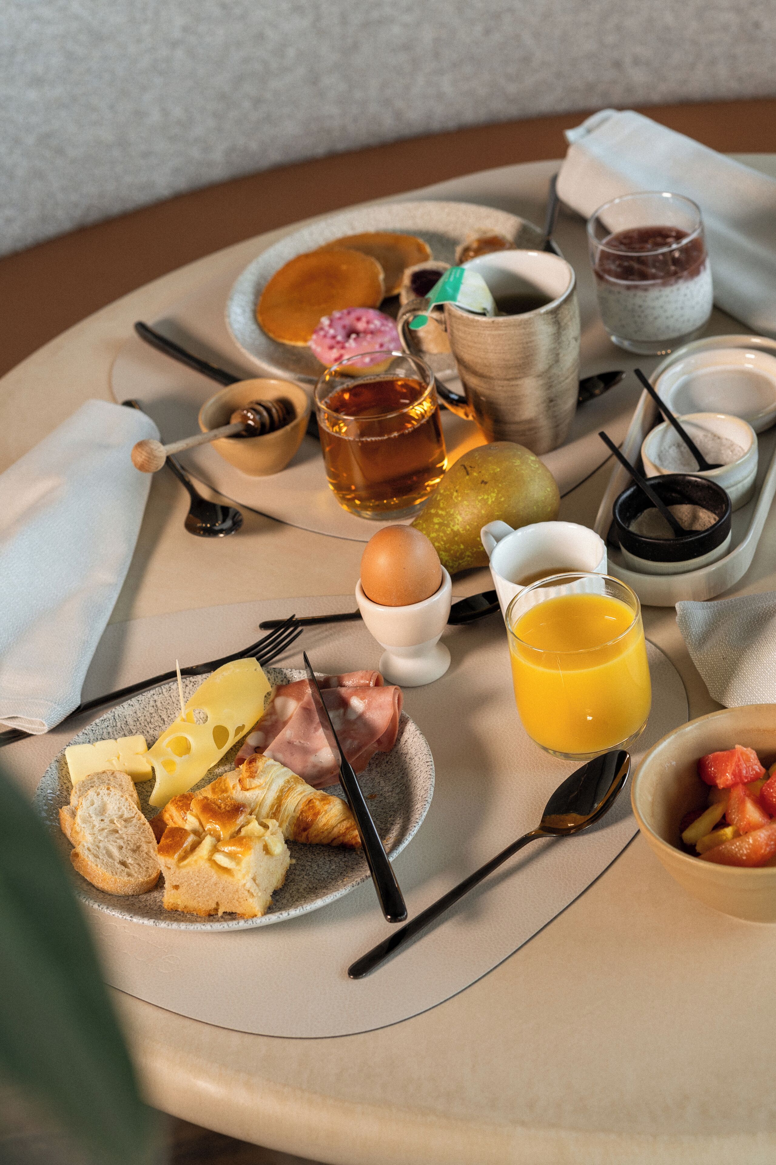 Ein Frühstücksbrett mit Eiern, Toast, Käse, Schinken, Obst und Getränken.