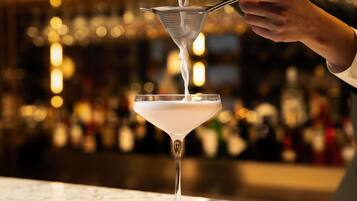 Un barman sirviendo una bebida en una copa de martini.